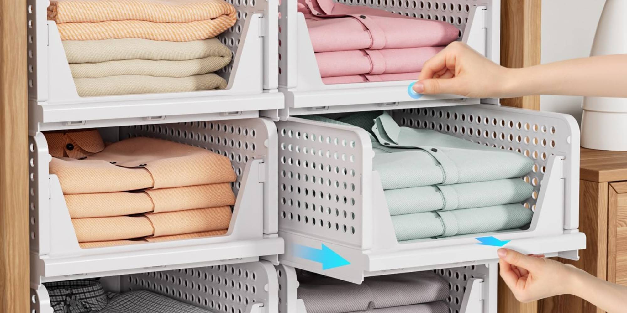 A hand picking up a stack of folded clothes