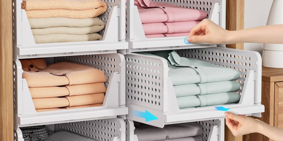 A hand picking up a stack of folded clothes