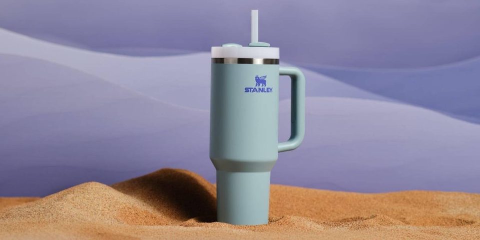 A blue and white coffee mug in sand