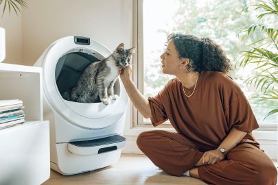 A woman sitting on the floor with a cat in a dryer