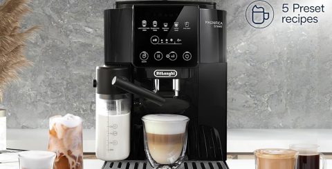 A black coffee machine with a glass of milk in it