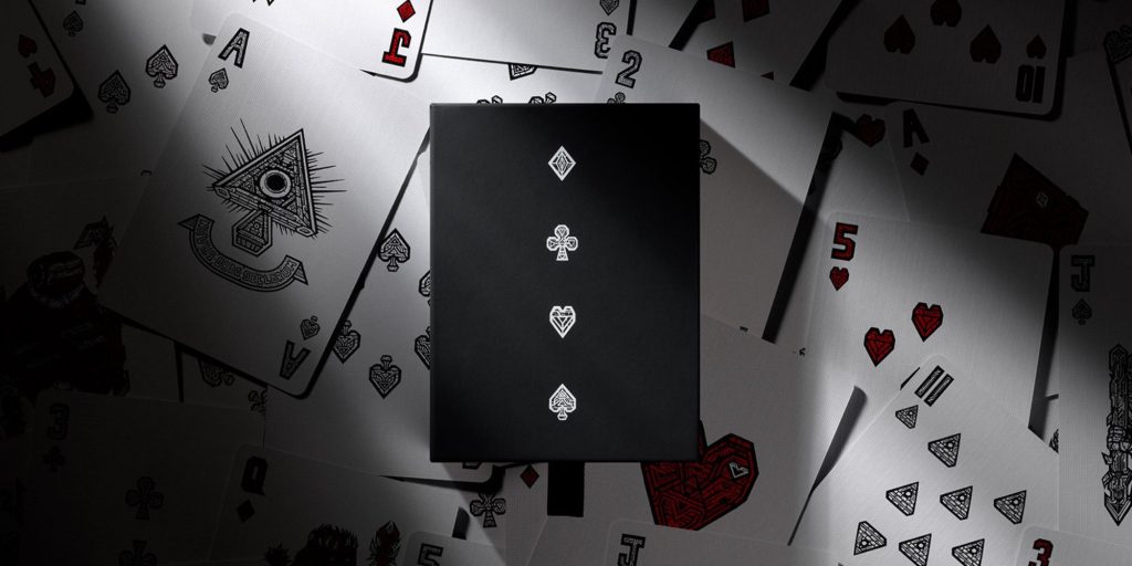 A black box with a black cover on top of playing cards