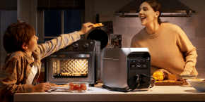 A woman taking a pizza out of a toaster oven