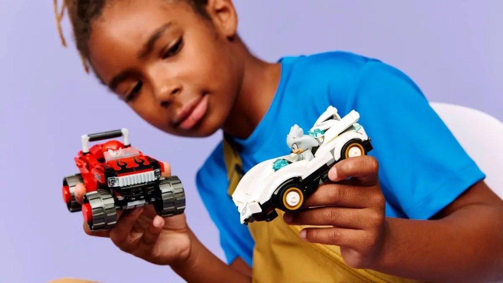 A boy holding two toy cars