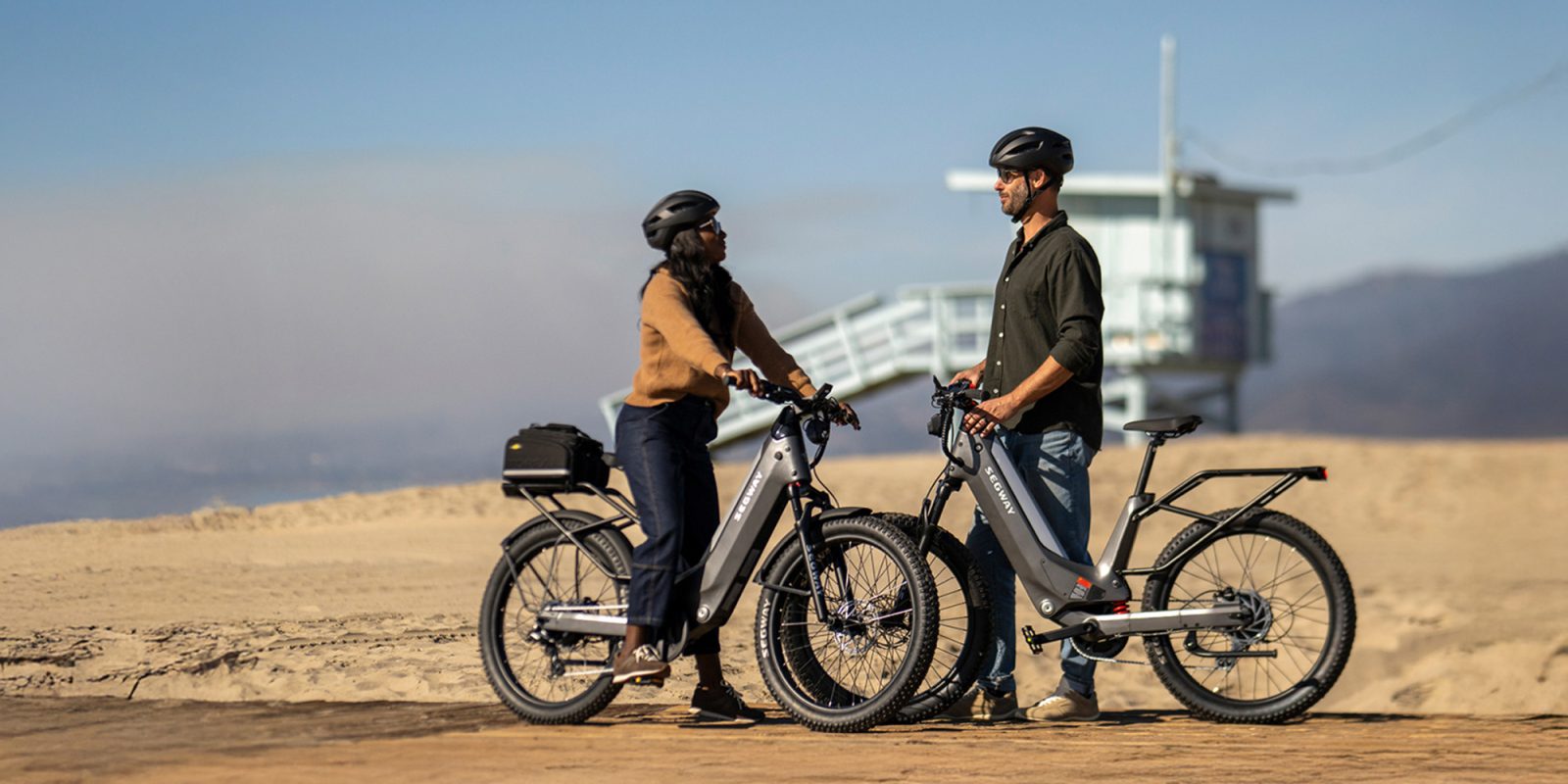A man and woman standing next to electric bikes