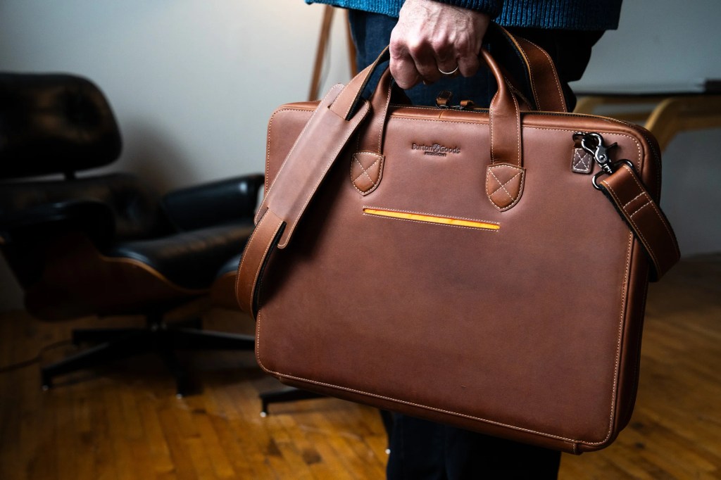 A person holding a brown briefcase