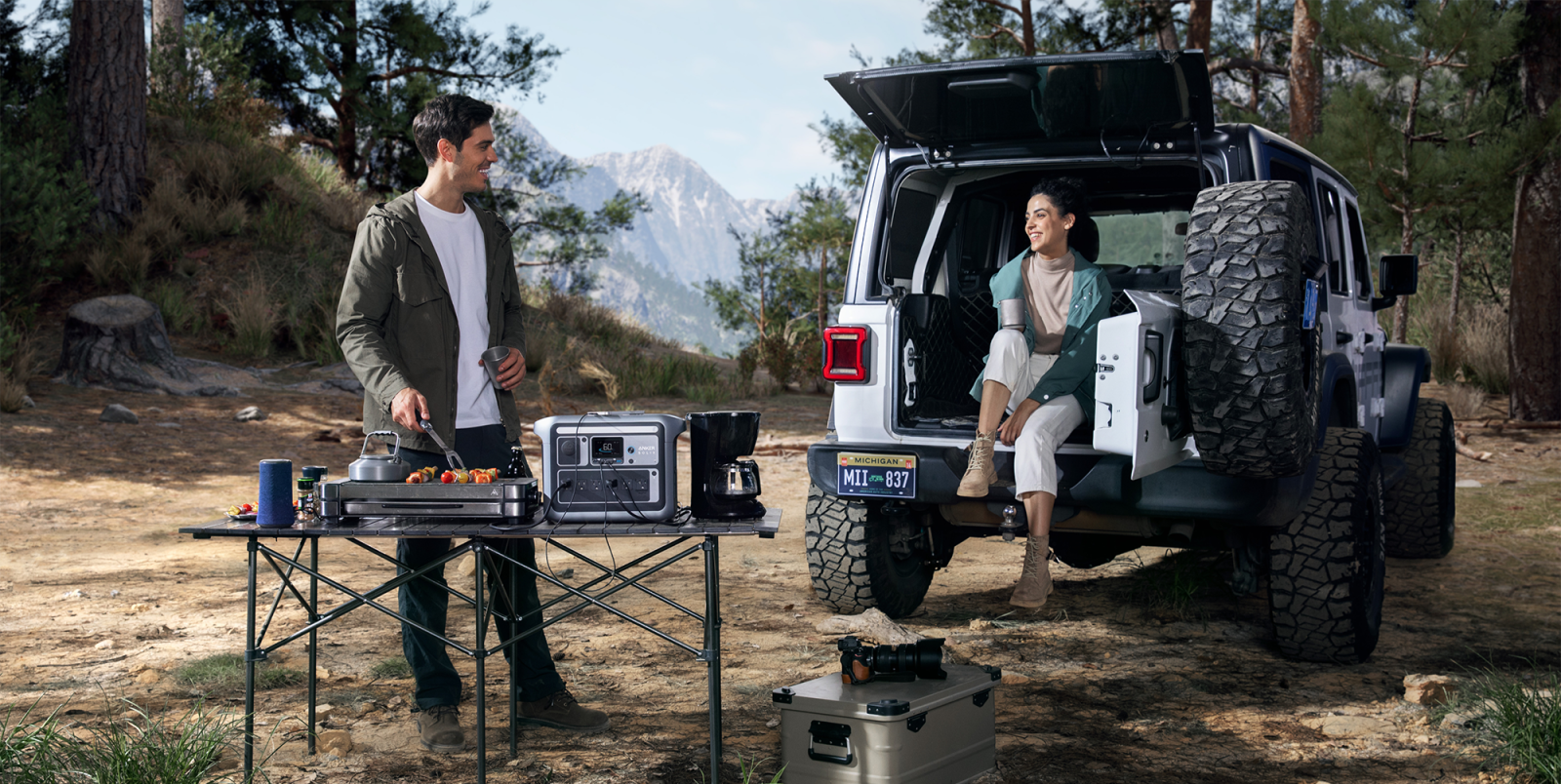 A man and woman cooking food in the back of a car