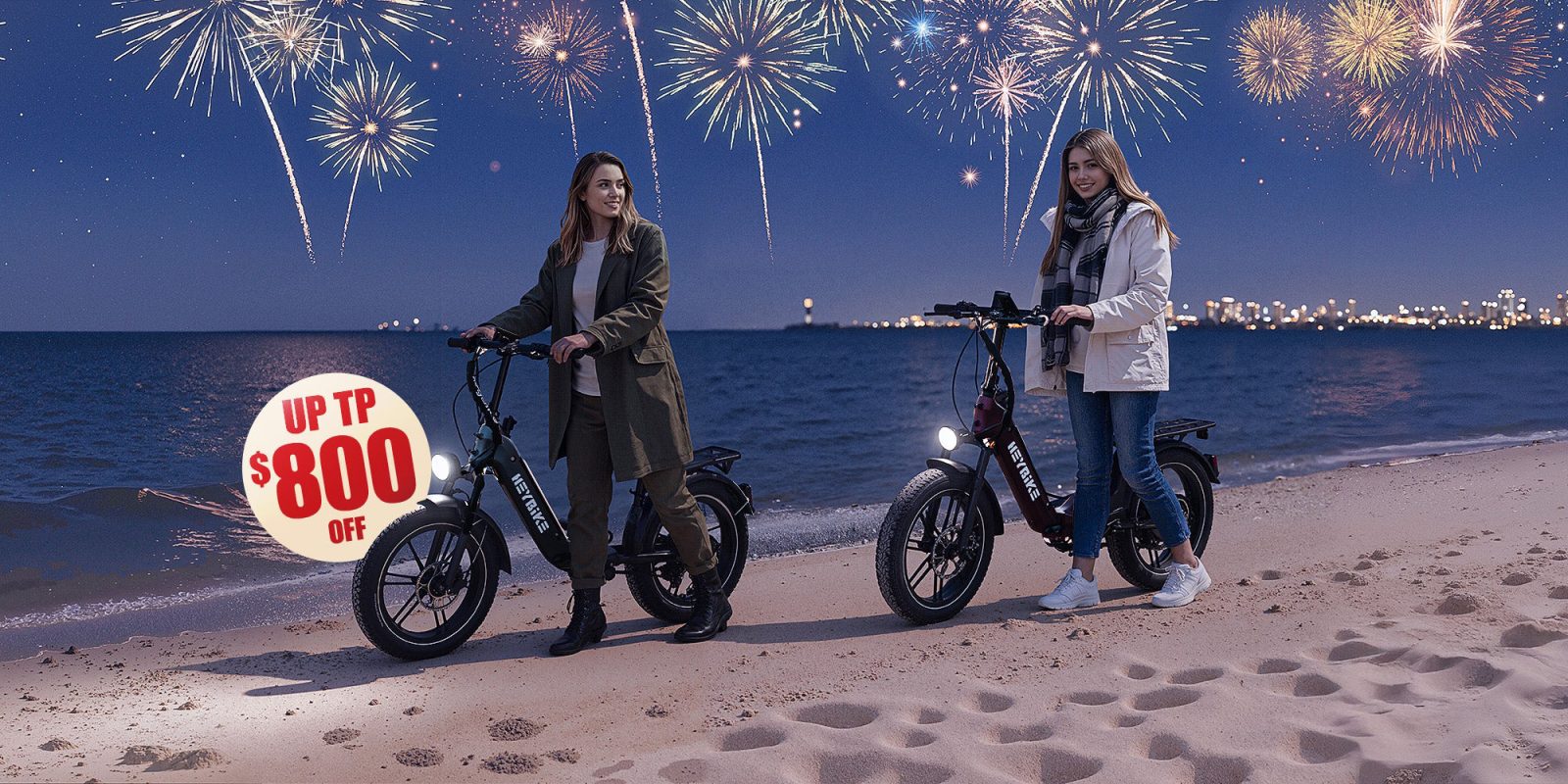 Two women standing on a beach with bikes and fireworks in the background