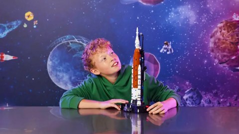 A boy sitting at a table with a toy rocket
