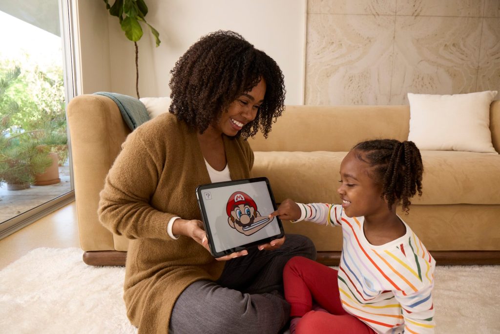 A woman and a child sitting on the floor looking at a tablet