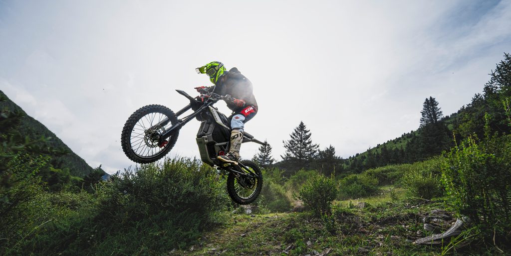 A person on a motorcycle jumping off a trail