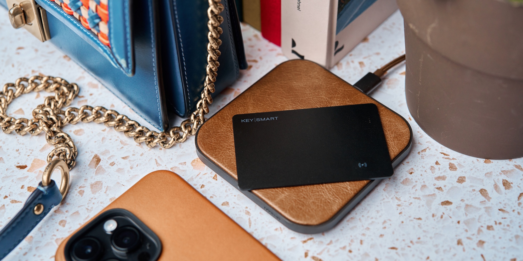 A black card on a brown leather case next to a gold chain