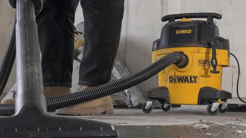 A person vacuuming a yellow vacuum