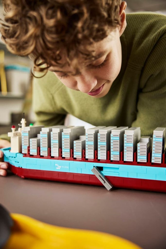 A boy playing with a LEGO Maersk ship