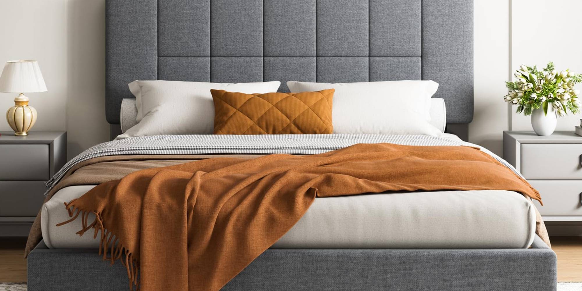 A bed with orange blanket and pillows