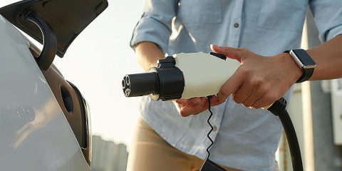 A person holding a plug in to a car