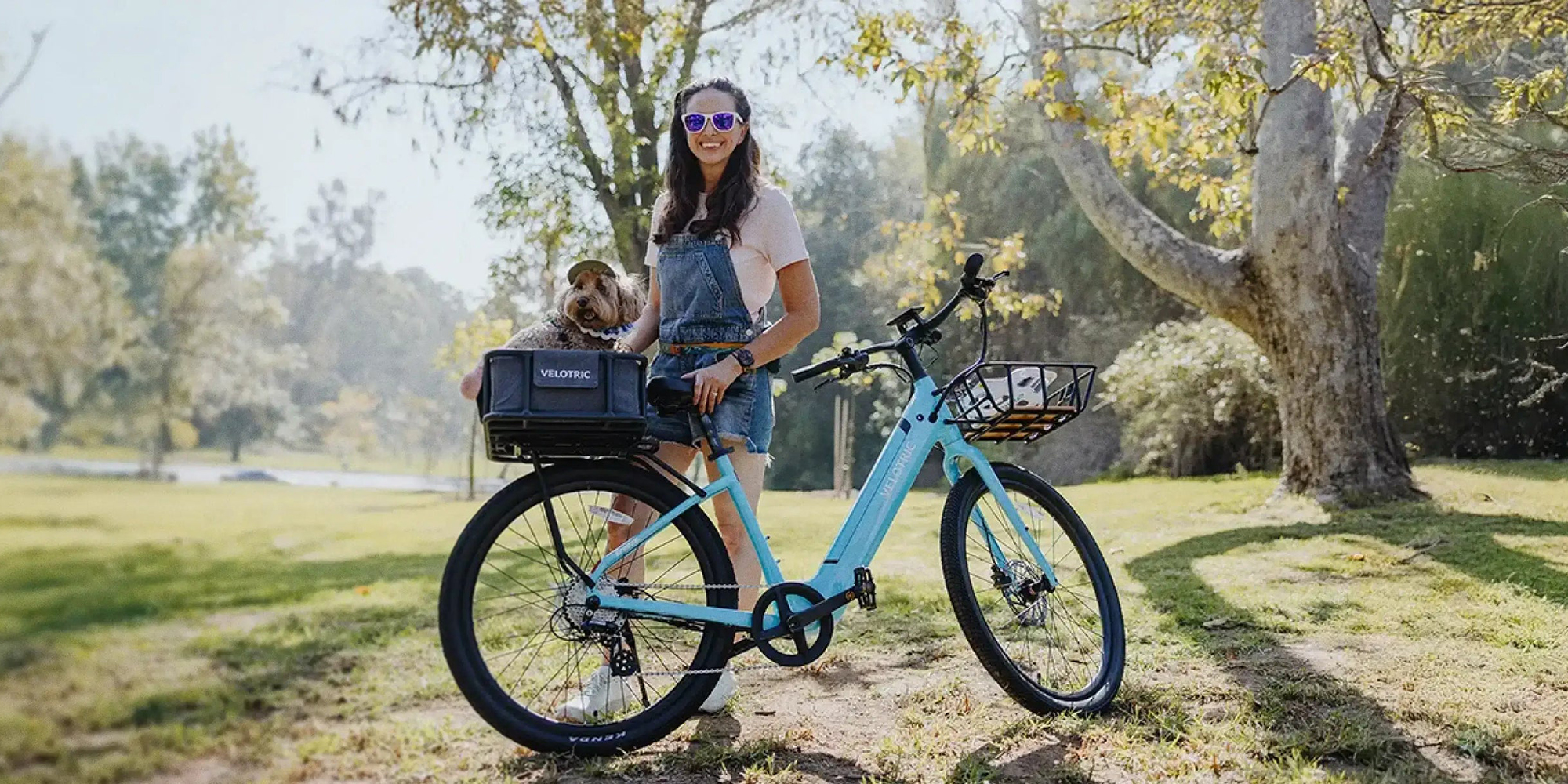 A woman standing next to a bicycle with a dog in her hand