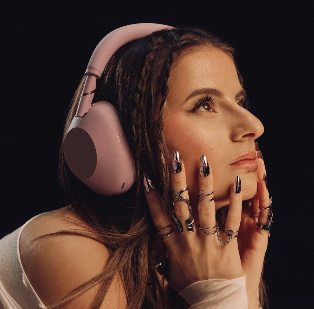 A woman wearing headphones and holding her hands to her face