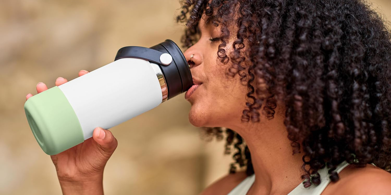 A woman drinking from a white mug