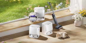 A cat lying on a window sill next to a vacuum cleaner