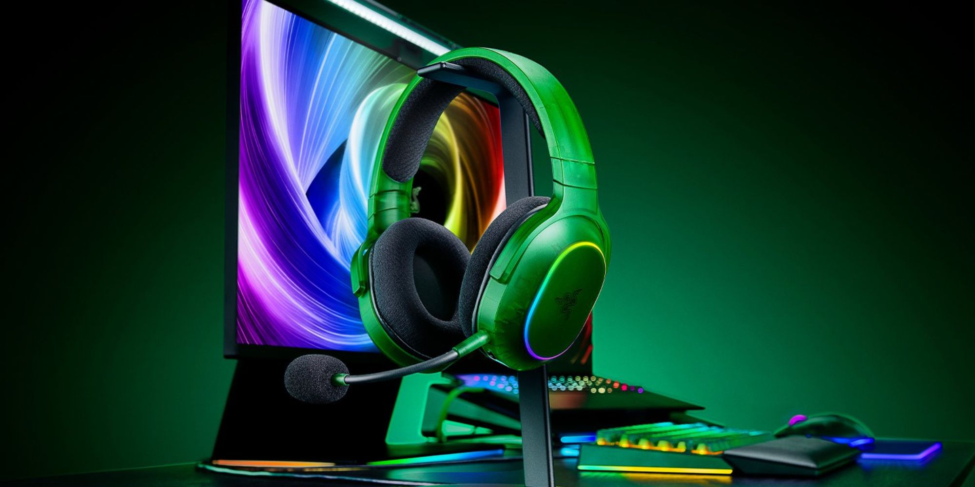 A green headphones on a stand next to a computer monitor