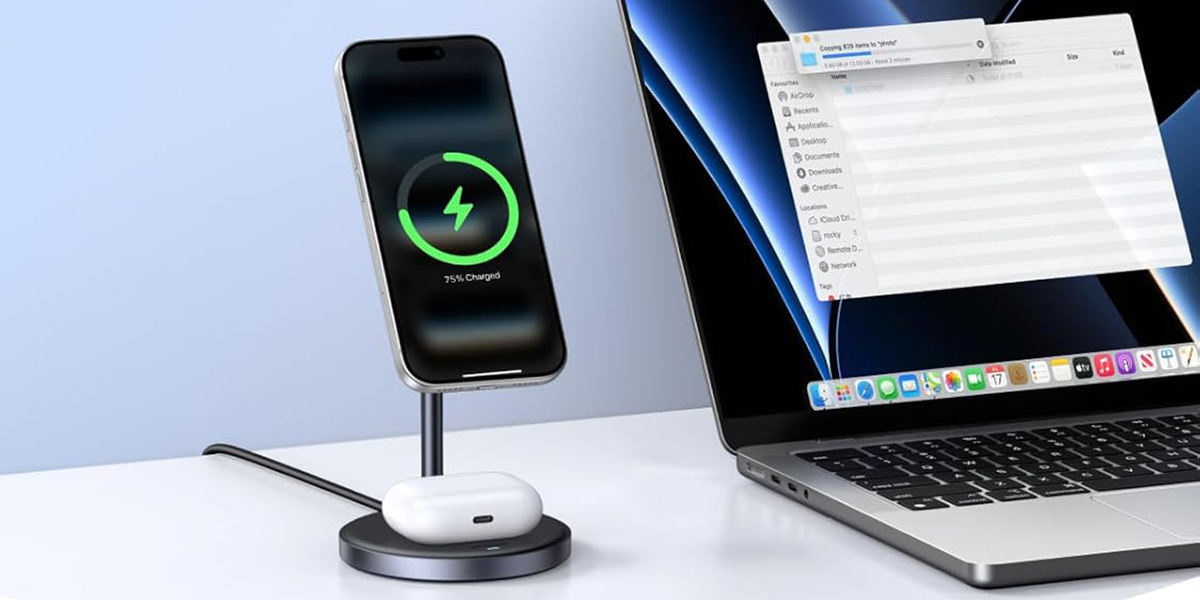 A cell phone charging on a charging pad next to a laptop