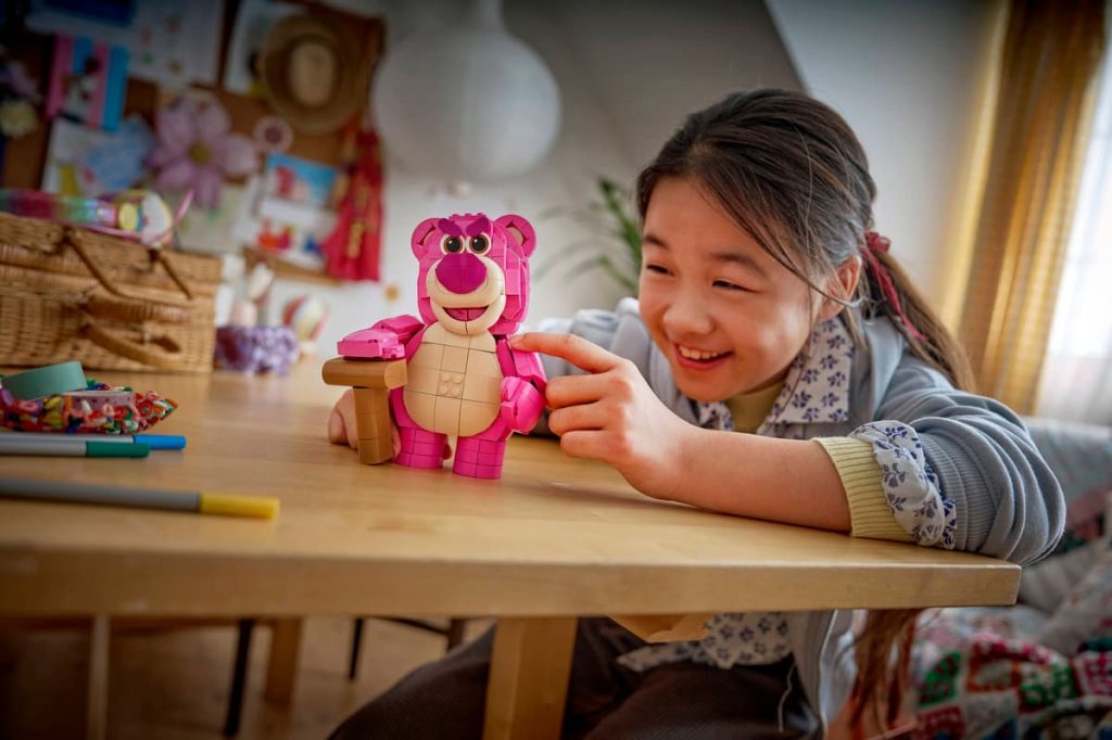 A girl smiling at a table with LEGO Toy Story set