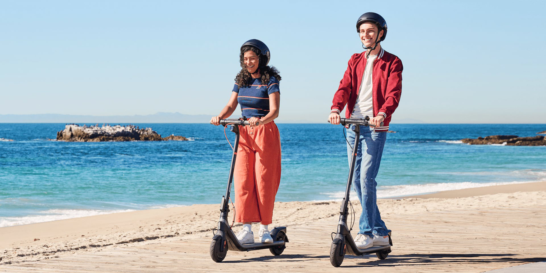 A man and woman riding scooters on a beach