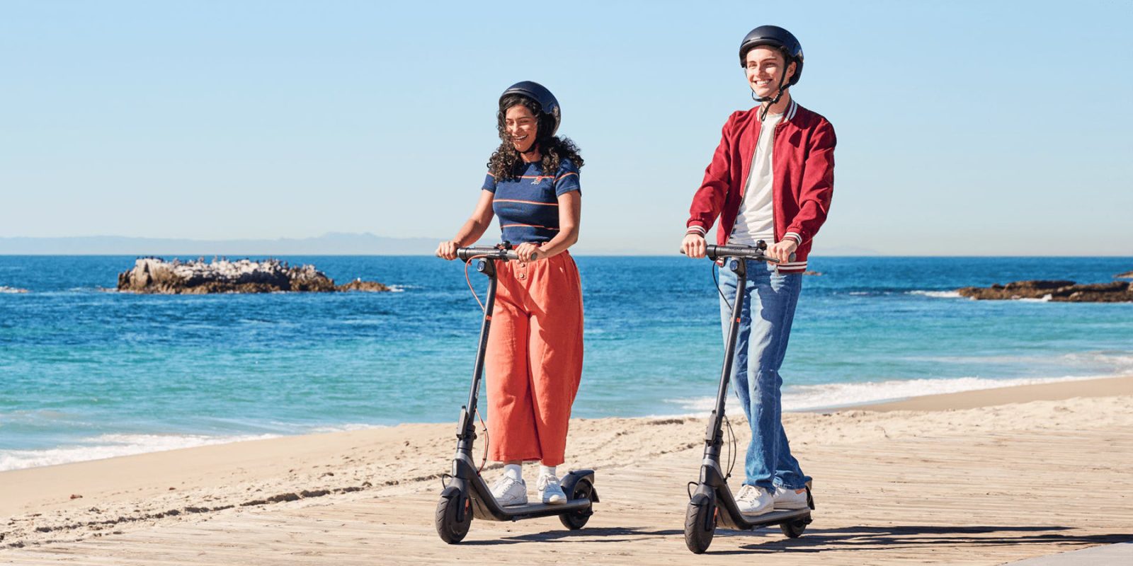 A man and woman riding scooters on a beach