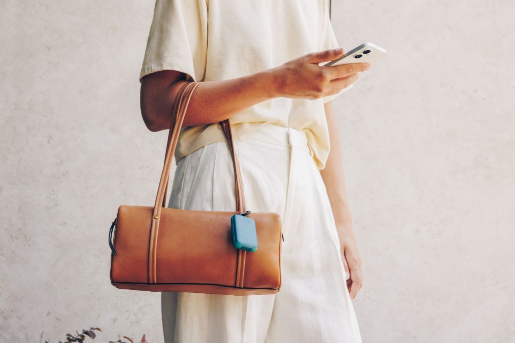 A person holding a purse and a cell phone