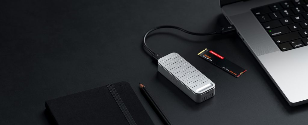 A silver rectangular device with a black pencil and a black notebook