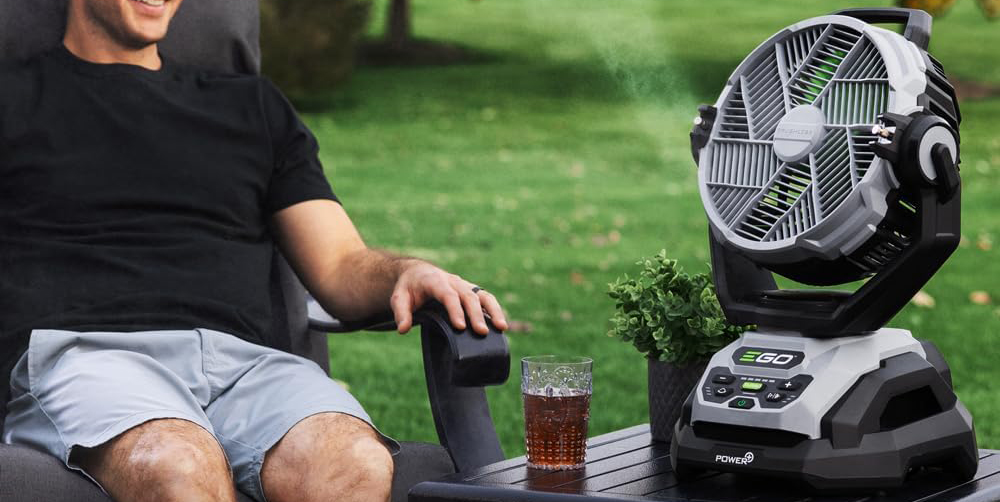 A man sitting in a chair outside with a glass of liquid
