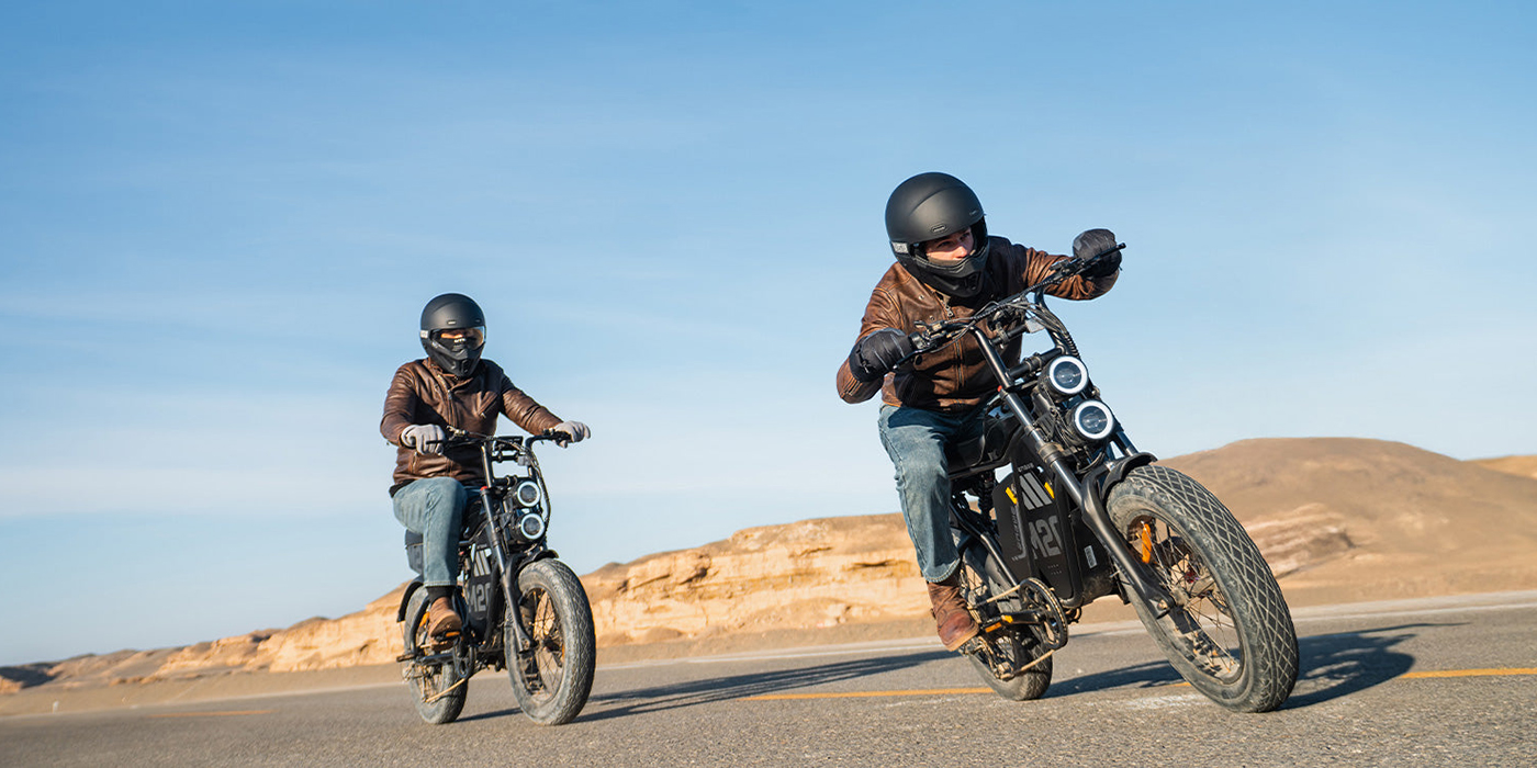 Two people riding motorcycles on a road