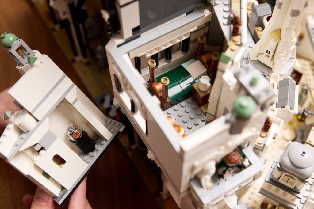 A person holding a building made of legos
