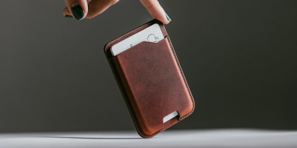 A hand holding a card in a leather case