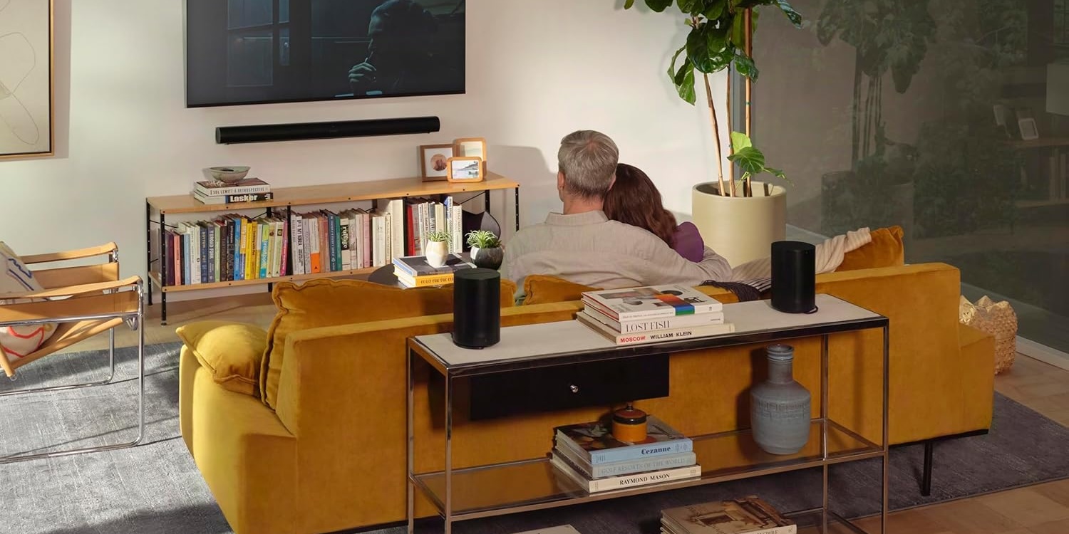 A man and woman sitting on a couch watching a television