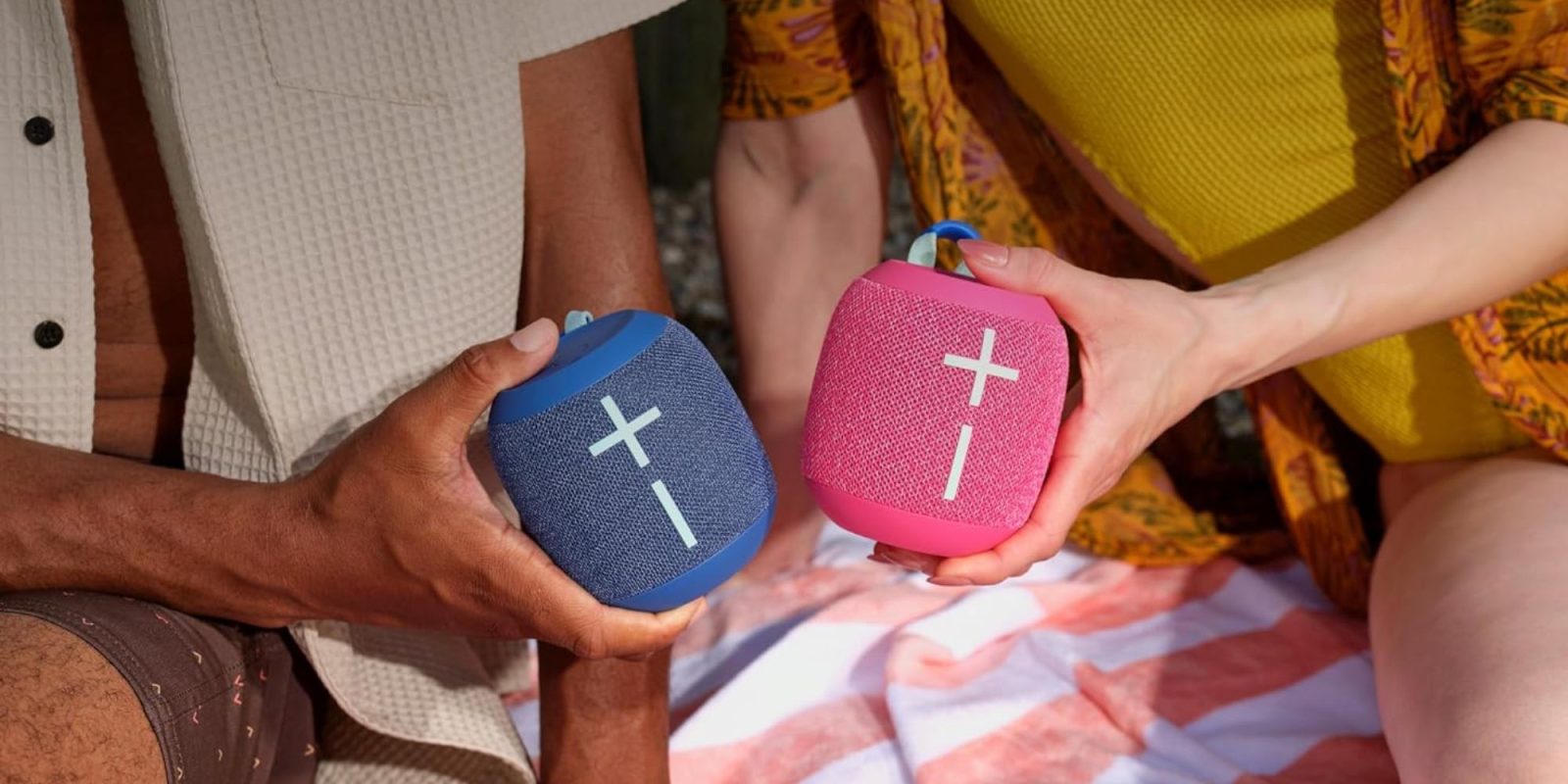 A group of people holding blue and pink speakers