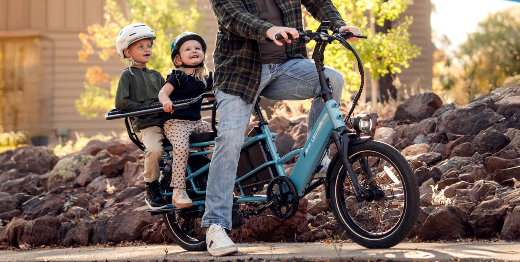 A man riding a bicycle with two children