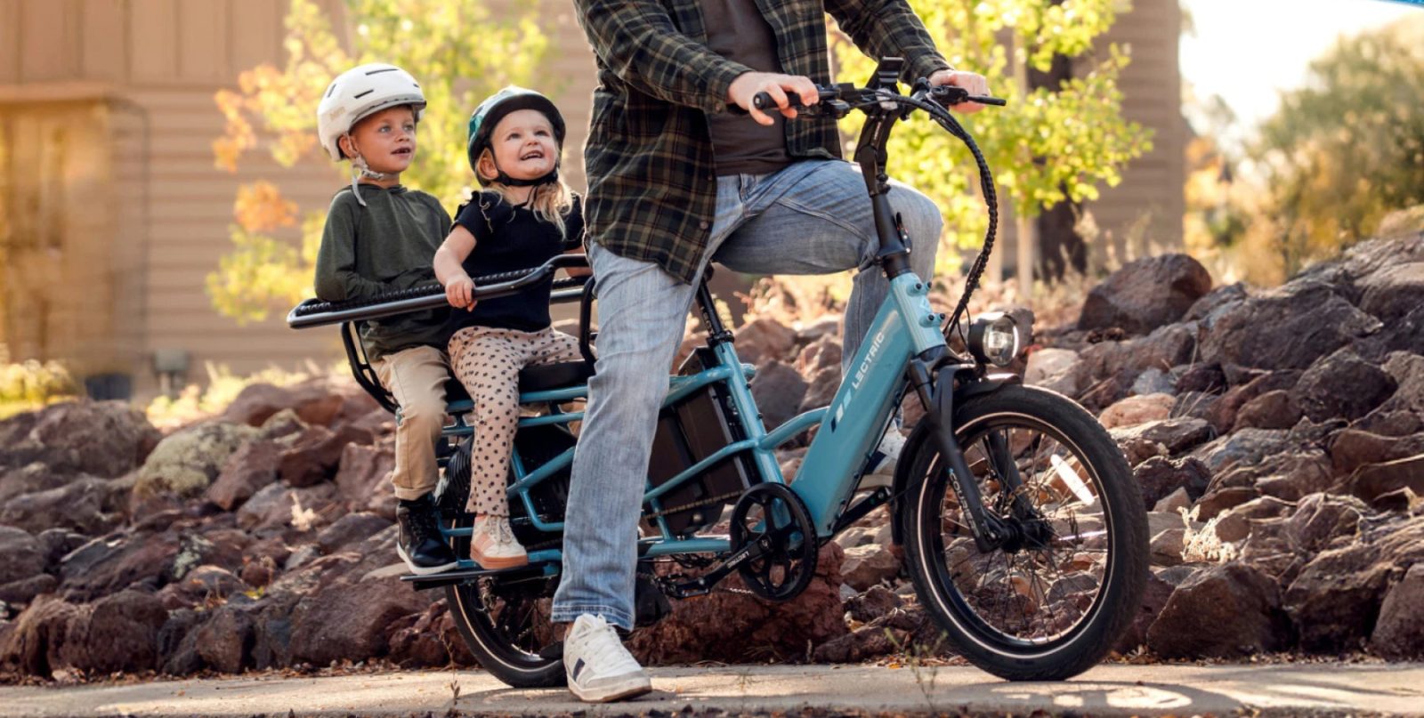 A man riding a bicycle with two children