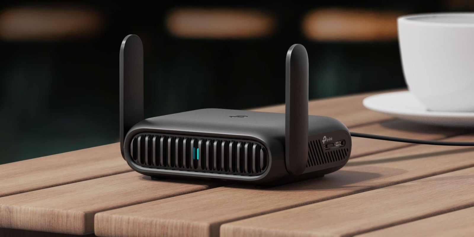 A black wireless router on a wood table