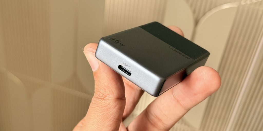 A hand holding a small square device