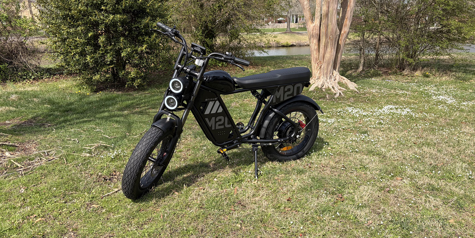 A black motorcycle parked on grass next to a tree