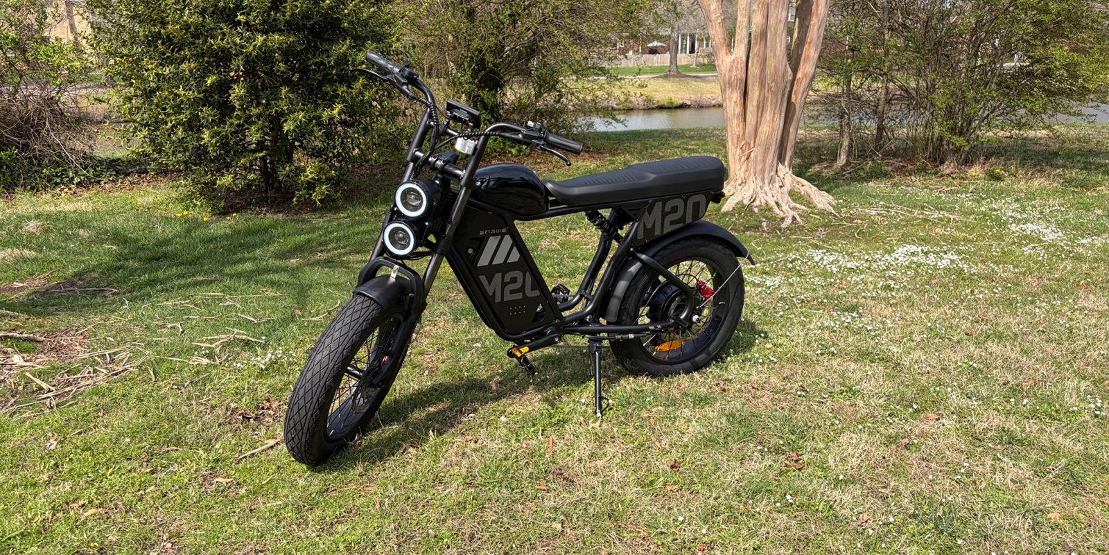 A black motorcycle parked on grass next to a tree