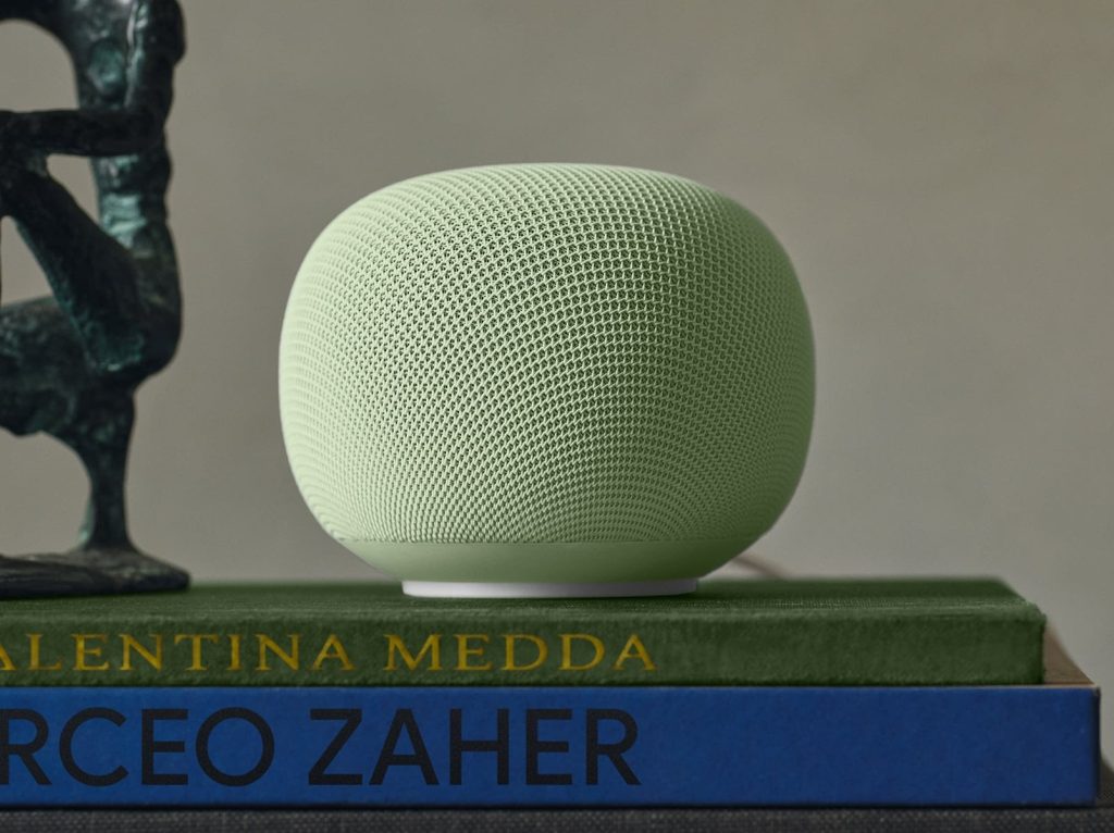 A green speaker on top of a stack of books