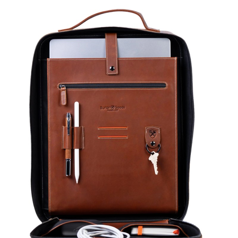 A brown leather briefcase with a laptop and pen and key