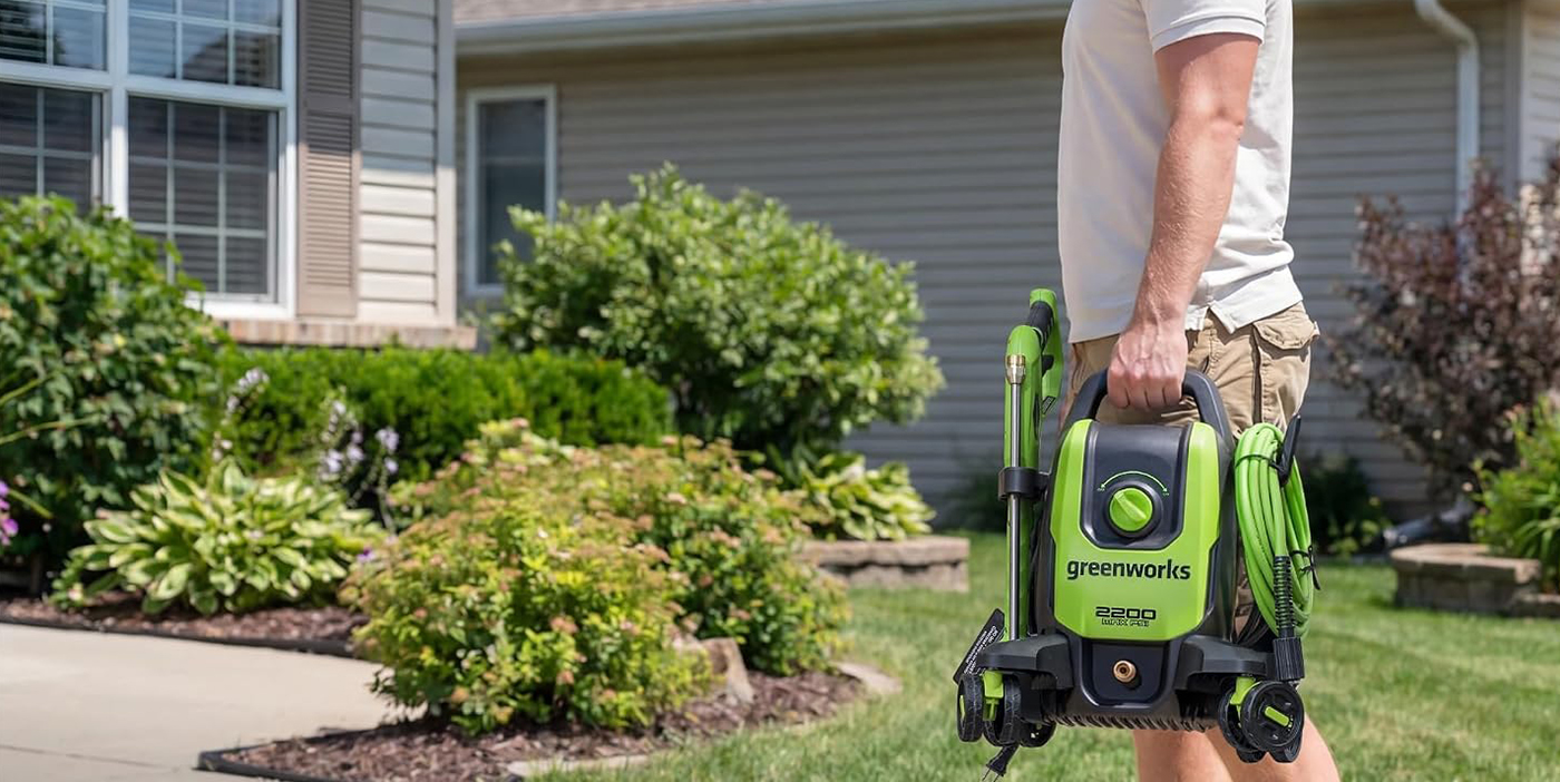 A person holding a green and black lawn mower