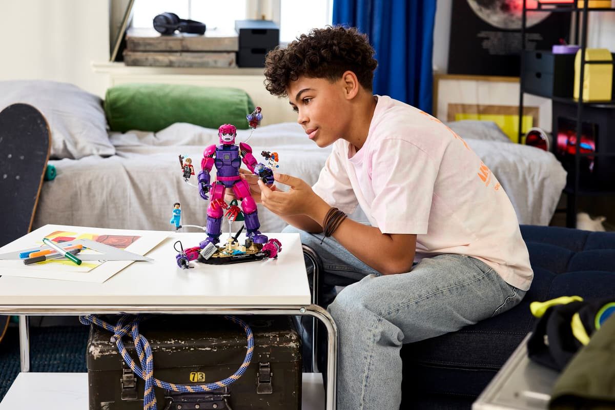 A boy sitting on a bed looking at a toy figurine