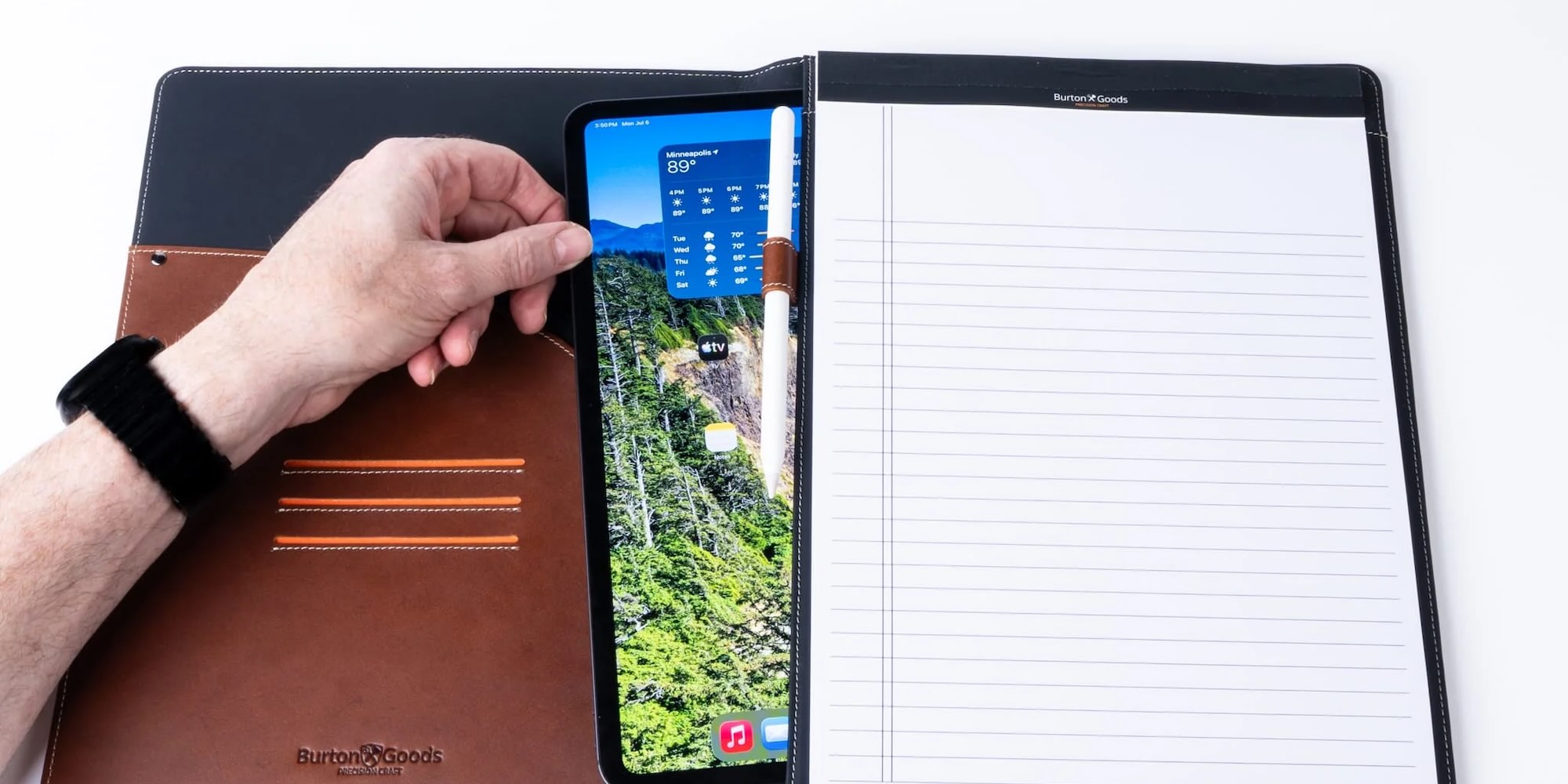 A hand holding a tablet with a pen in it