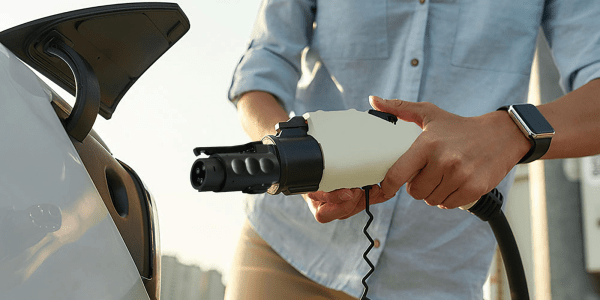 A person holding a plug in to a car