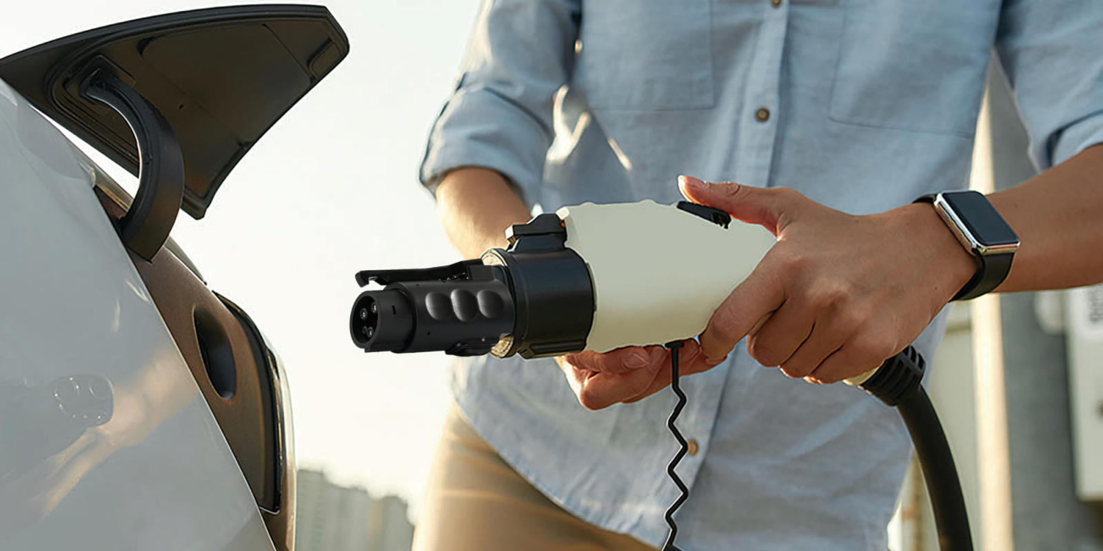 A person holding a plug in to a car
